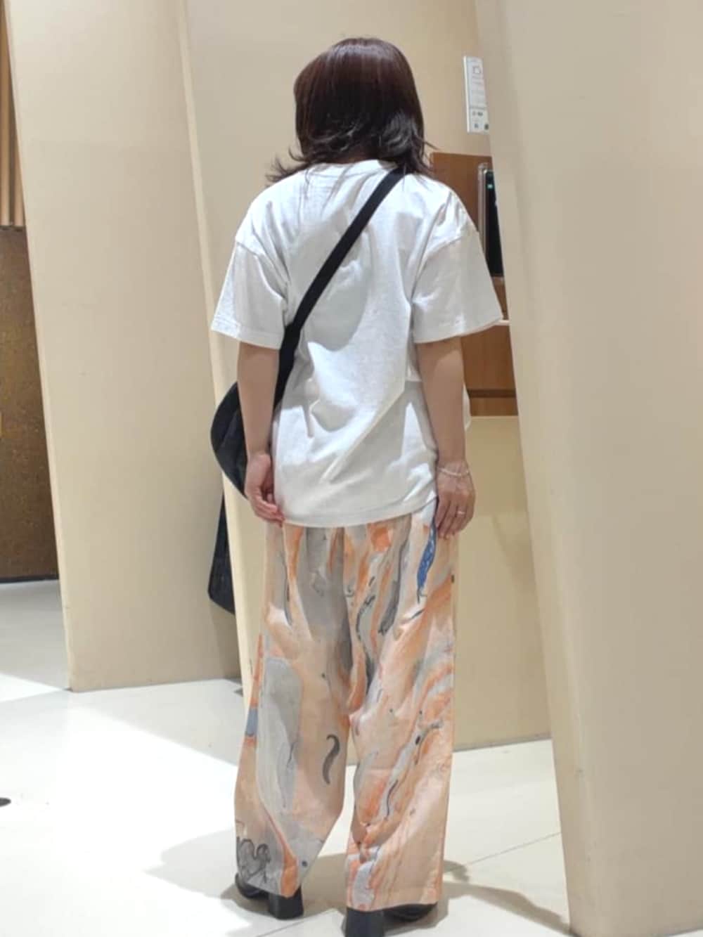 ブラック系のショルダーバッグ、オレンジ系のその他パンツ、ホワイト系のTシャツ/カットソーを着用したレディースの春コーディネートの4枚目の写真