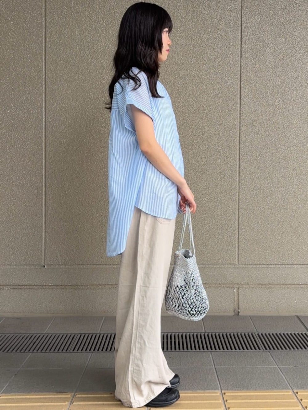 ベージュ系のデニムパンツ、シルバー系のハンドバッグ、ブルー系のシャツ/ブラウスを着用したレディースの夏コーディネートの2枚目の写真