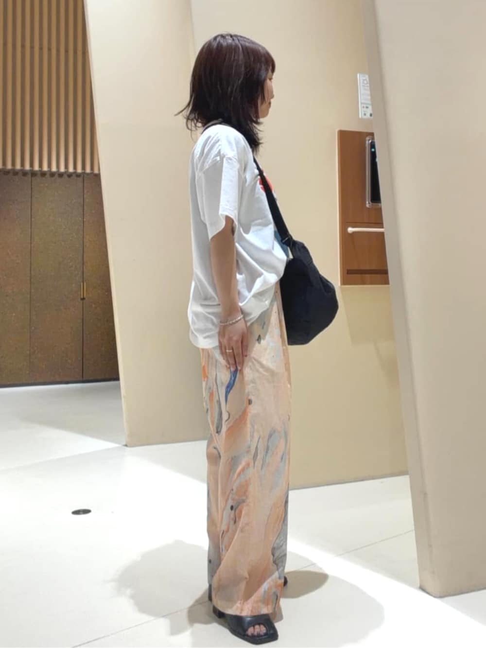 ブラック系のショルダーバッグ、オレンジ系のその他パンツ、ホワイト系のTシャツ/カットソーを着用したレディースの春コーディネートの3枚目の写真