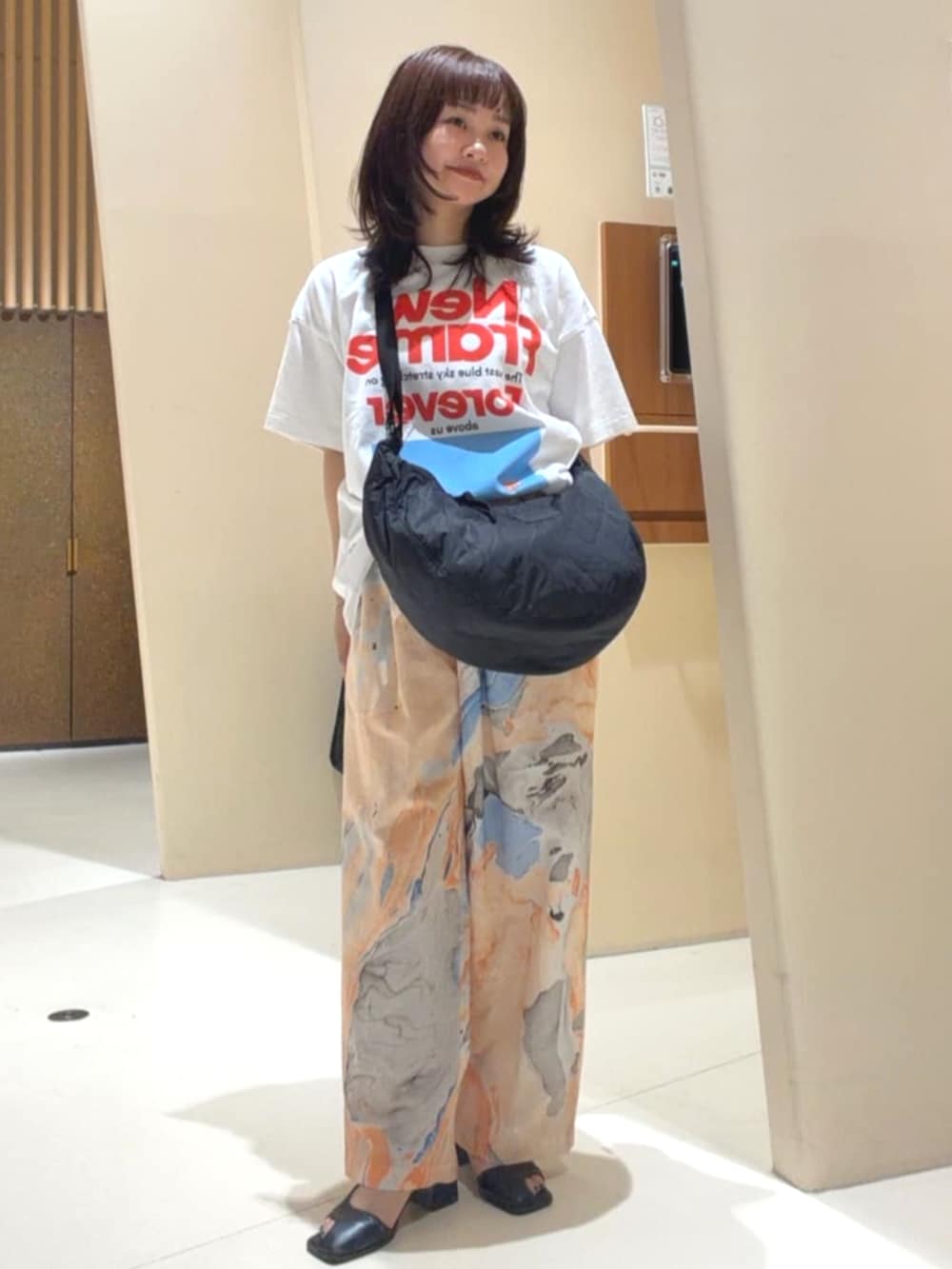 ブラック系のショルダーバッグ、オレンジ系のその他パンツ、ホワイト系のTシャツ/カットソーを着用したレディースの春コーディネートの2枚目の写真