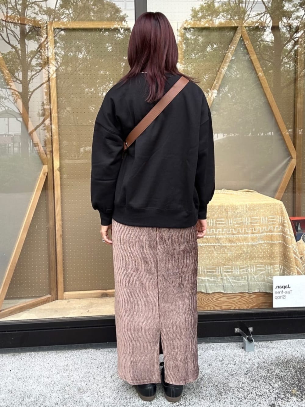 ブラウン系のショルダーバッグ、ブラック系のスウェット、イエロー系のスカートを着用したレディースの秋コーディネートの2枚目の写真