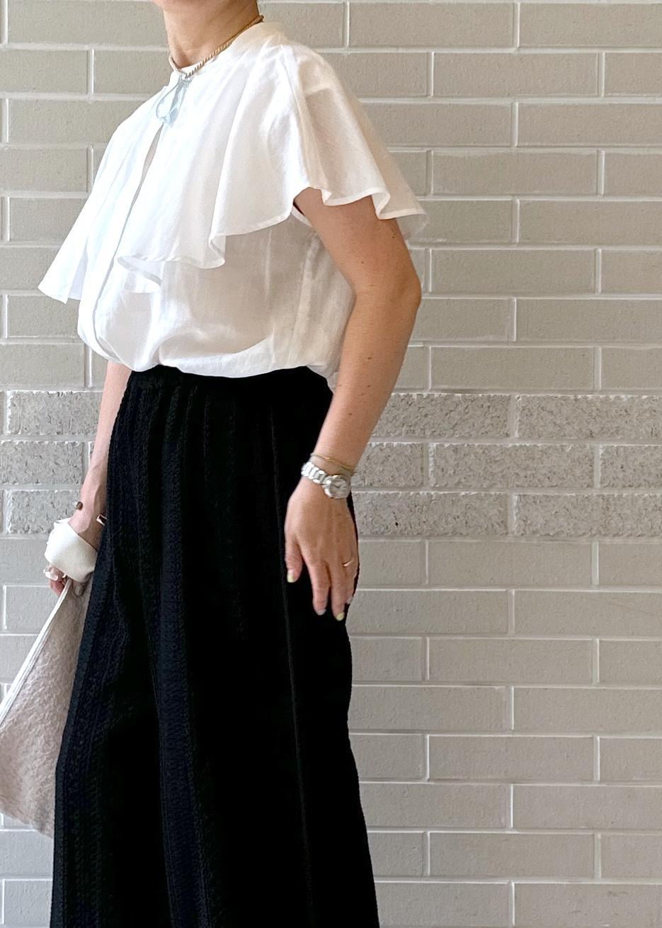 ブラック系のその他パンツ、ブラック系のサンダル、ベージュ系のクラッチバッグを着用したレディースの夏コーディネートの3枚目の写真