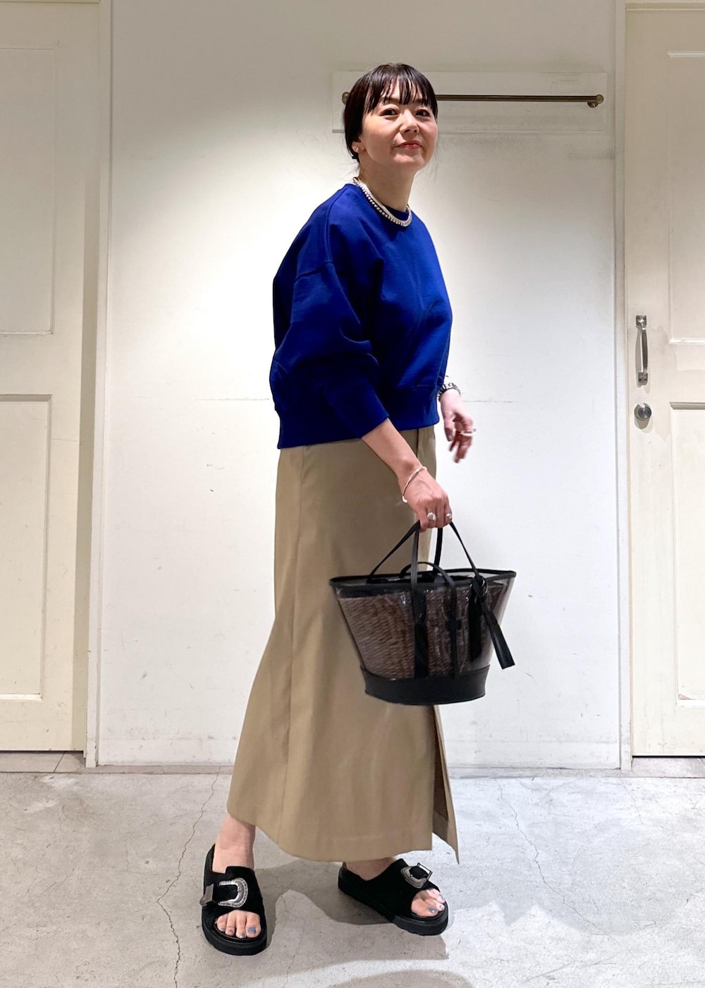 ブルー系のスウェット、ベージュ系のスカート、ブラック系のサンダルを着用したレディースの冬コーディネートの2枚目の写真
