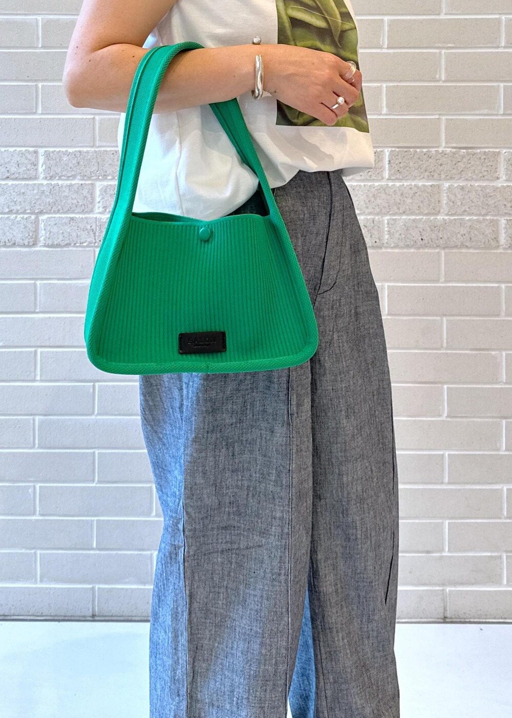 ホワイト系のTシャツ/カットソー、ブラック系のサンダル、グリーン系のハンドバッグを着用したレディースの夏コーディネートの5枚目の写真