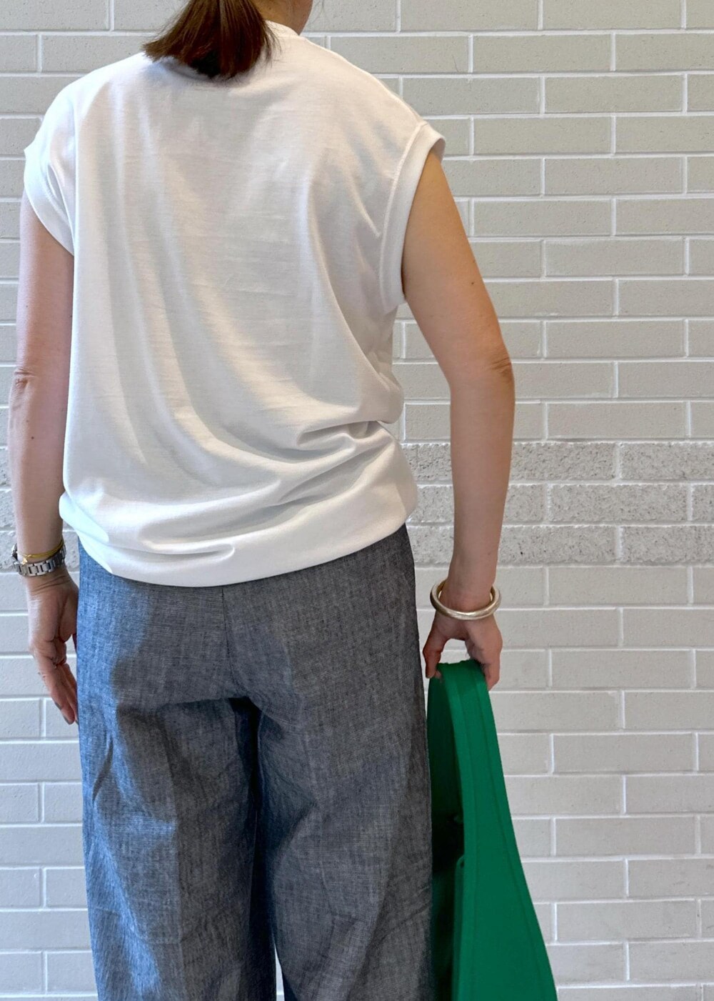 ホワイト系のTシャツ/カットソー、ブラック系のサンダル、グリーン系のハンドバッグを着用したレディースの夏コーディネートの4枚目の写真