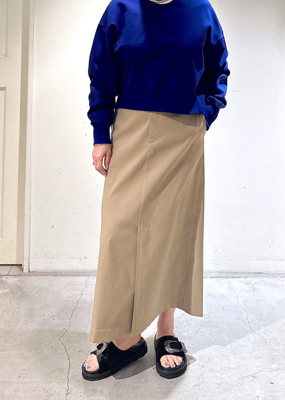 ブルー系のスウェット、ベージュ系のスカート、ブラック系のサンダルを着用したレディースの冬コーディネートの3枚目の写真