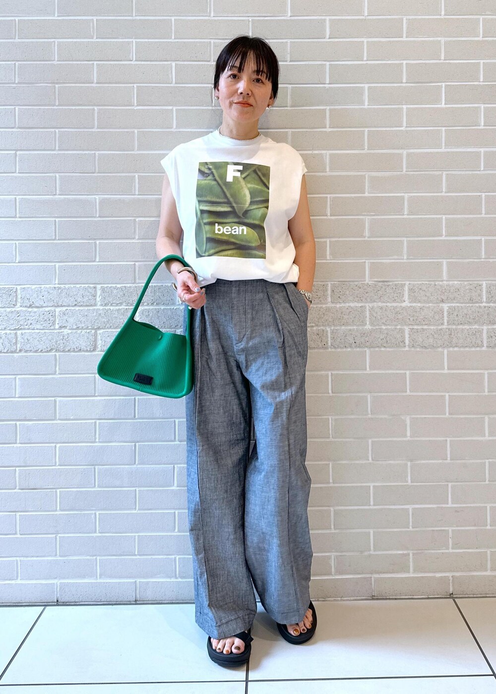 ホワイト系のTシャツ/カットソー、ブラック系のサンダル、グリーン系のハンドバッグを着用したレディースの夏コーディネートの2枚目の写真