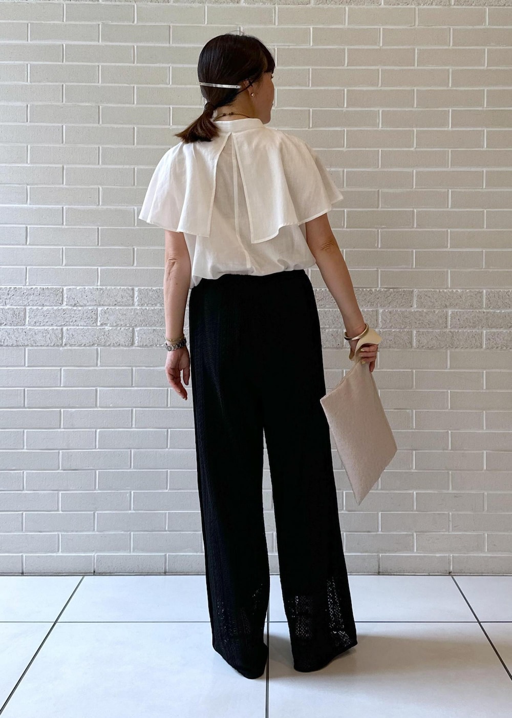 ブラック系のその他パンツ、ブラック系のサンダル、ベージュ系のクラッチバッグを着用したレディースの夏コーディネートの4枚目の写真