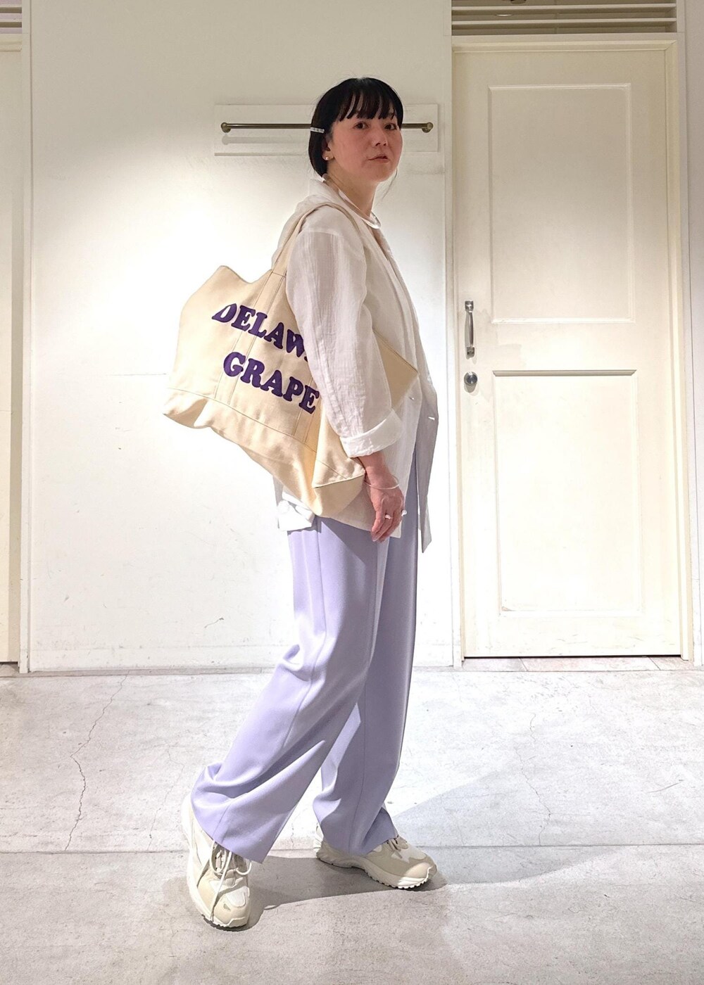 パープル系のスラックス、ホワイト系のテーラードジャケット、ホワイト系のスニーカーを着用したレディースの冬コーディネートの2枚目の写真