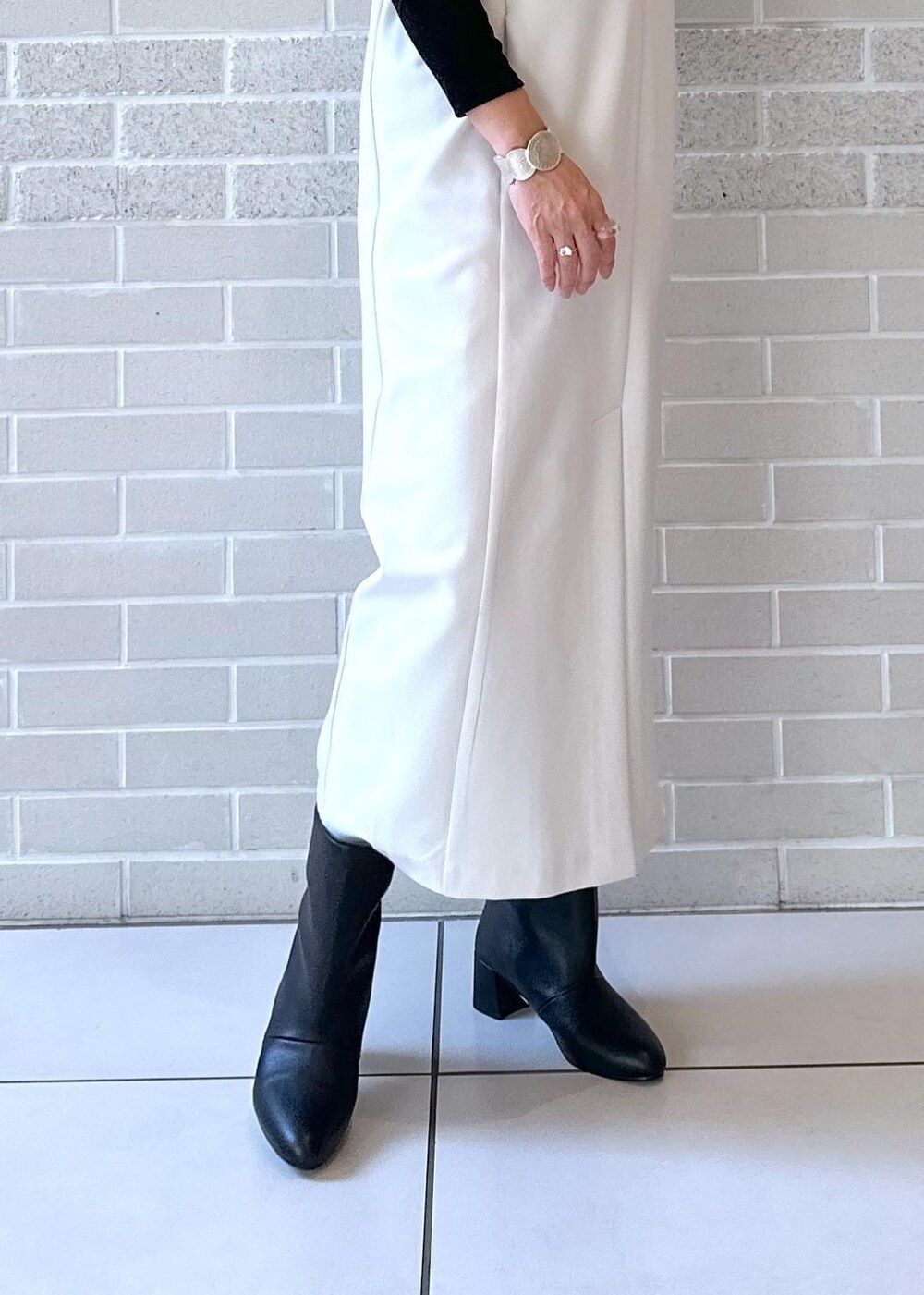 ブラック系のブーツ、ブラック系のジャンパースカート、ブラック系のTシャツ/カットソーを着用したレディースの秋コーディネートの6枚目の写真