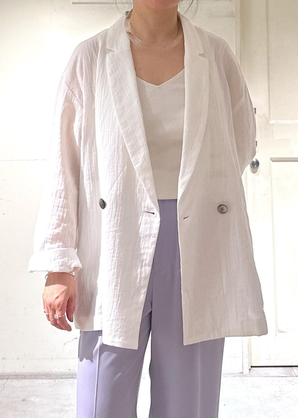 パープル系のスラックス、ホワイト系のテーラードジャケット、ホワイト系のスニーカーを着用したレディースの冬コーディネートの4枚目の写真