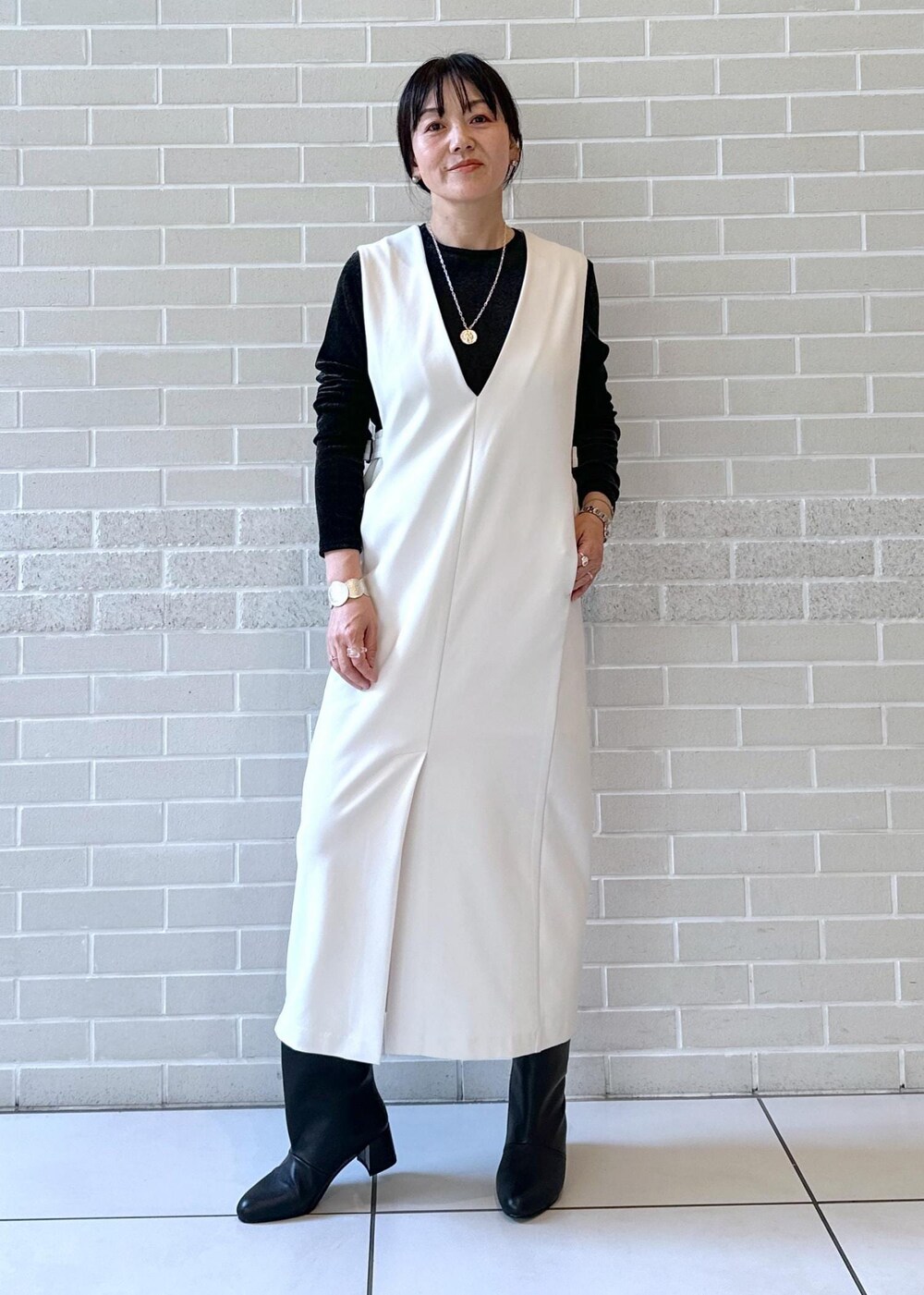 ブラック系のブーツ、ブラック系のジャンパースカート、ブラック系のTシャツ/カットソーを着用したレディースの秋コーディネートの2枚目の写真