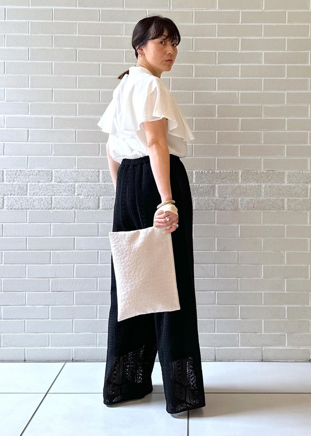 ブラック系のその他パンツ、ブラック系のサンダル、ベージュ系のクラッチバッグを着用したレディースの夏コーディネートの5枚目の写真