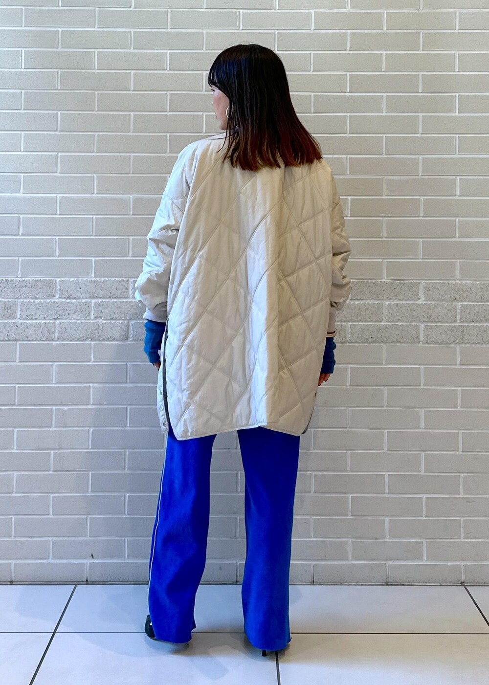 グレー系のブルゾン、ホワイト系のニット/セーター、ブルー系のその他パンツを着用したレディースの秋コーディネートの2枚目の写真