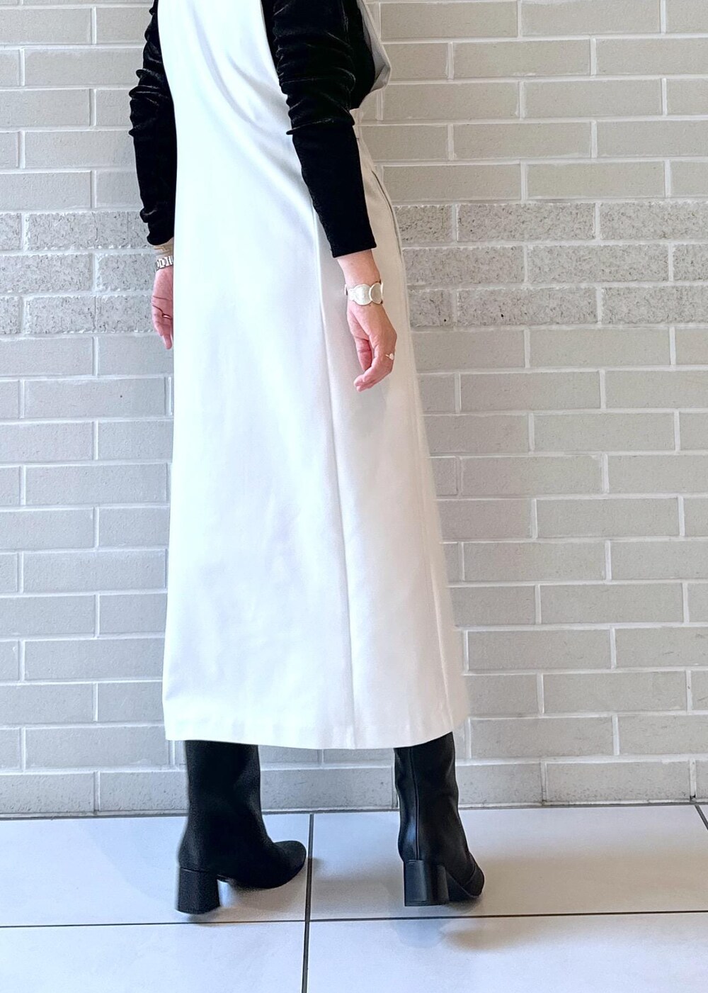 ブラック系のブーツ、ブラック系のジャンパースカート、ブラック系のTシャツ/カットソーを着用したレディースの秋コーディネートの7枚目の写真