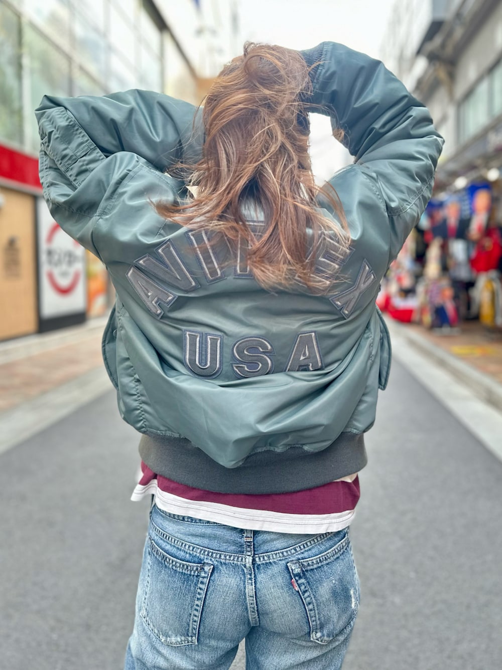 グリーン系のMA-1、レッド系のTシャツ/カットソーを着用したレディースの秋コーディネートの4枚目の写真