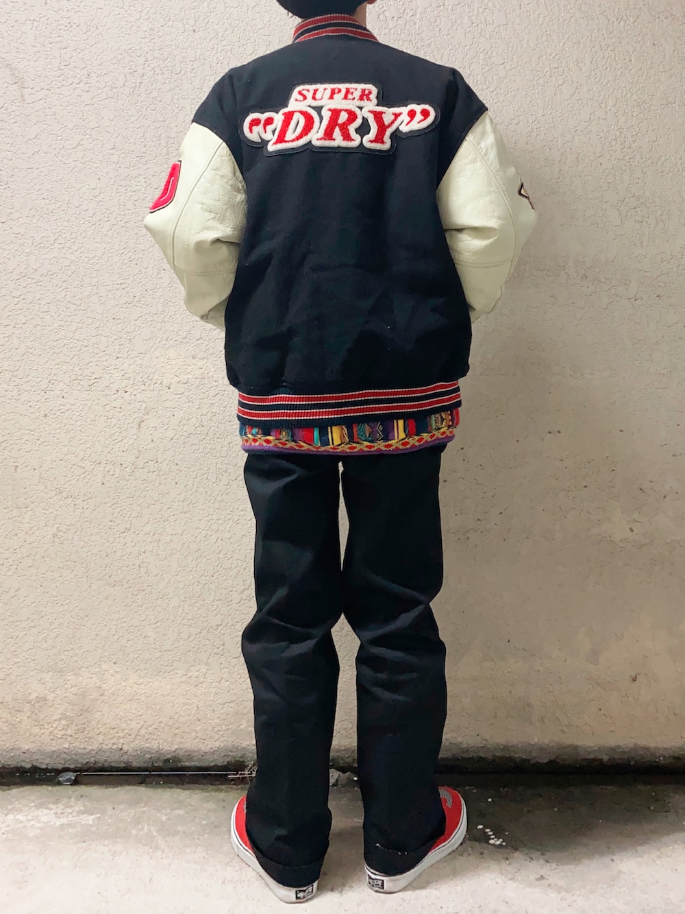 ブラック系のチノパンツ、レッド系のスニーカー、その他のスタジャンを着用したメンズの冬コーディネートの2枚目の写真