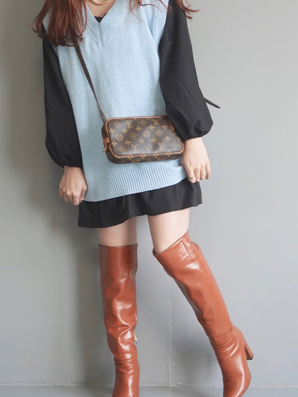 ブルー系のベスト、ブラック系のワンピース、ゴールド系のネックレスを着用したレディースの秋コーディネートの2枚目の写真