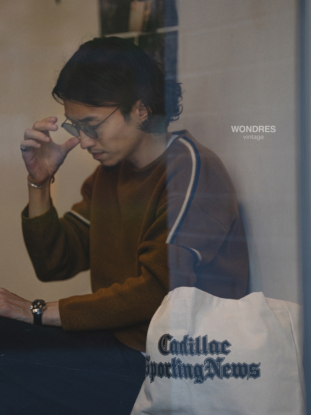 ブラウン系のニット/セーター、ブラック系のデニムパンツ、ブラック系のスニーカーを着用したメンズの秋コーディネートの2枚目の写真