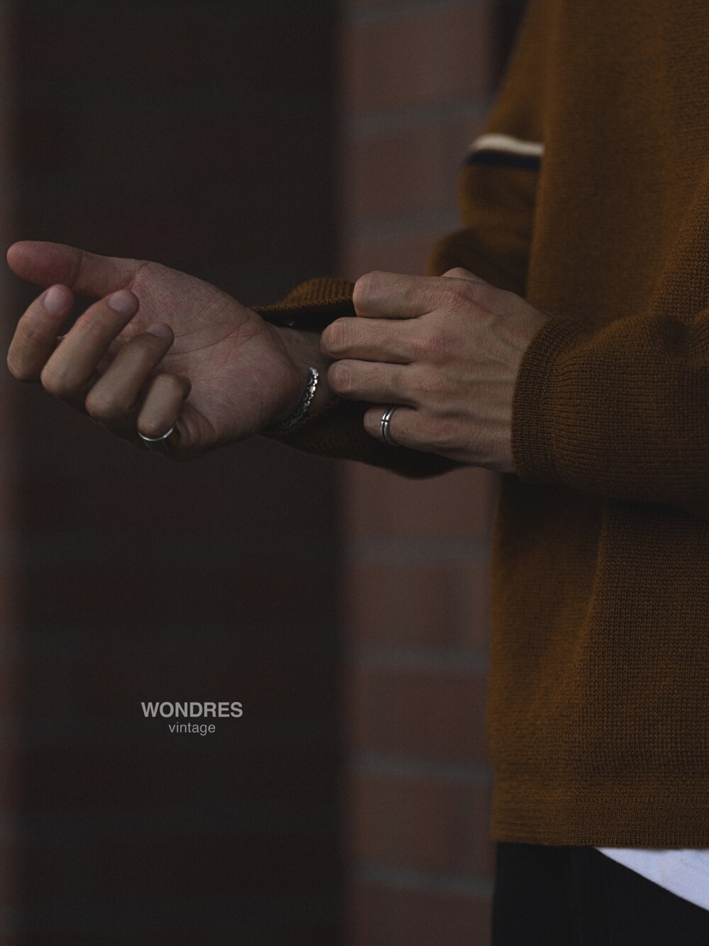 ブラウン系のニット/セーター、ブラック系のデニムパンツ、ブラック系のスニーカーを着用したメンズの秋コーディネートの4枚目の写真