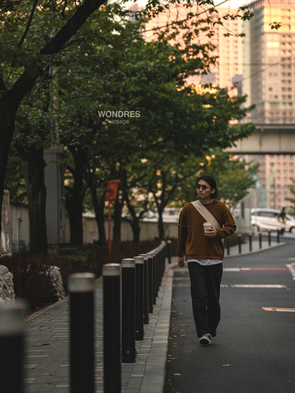 ブラウン系のニット/セーター、ブラック系のデニムパンツ、ブラック系のスニーカーを着用したメンズの秋コーディネートの5枚目の写真