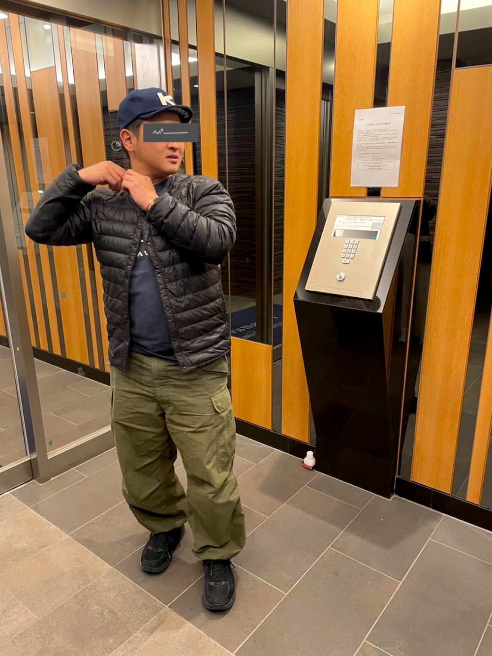 ブラック系のダウンジャケット/コート、ブルー系のTシャツ/カットソー、グリーン系のカーゴパンツを着用したメンズの秋コーディネートの2枚目の写真