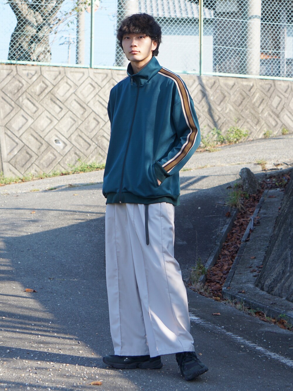 グリーン系のブルゾン、グレー系のその他パンツ、ブラック系のスニーカーを着用したメンズの秋コーディネートの2枚目の写真