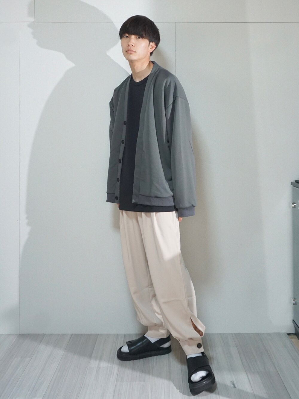 グレー系のカーディガン/ボレロ、ブラック系のTシャツ/カットソー、ベージュ系のその他パンツを着用したメンズの春コーディネートの2枚目の写真