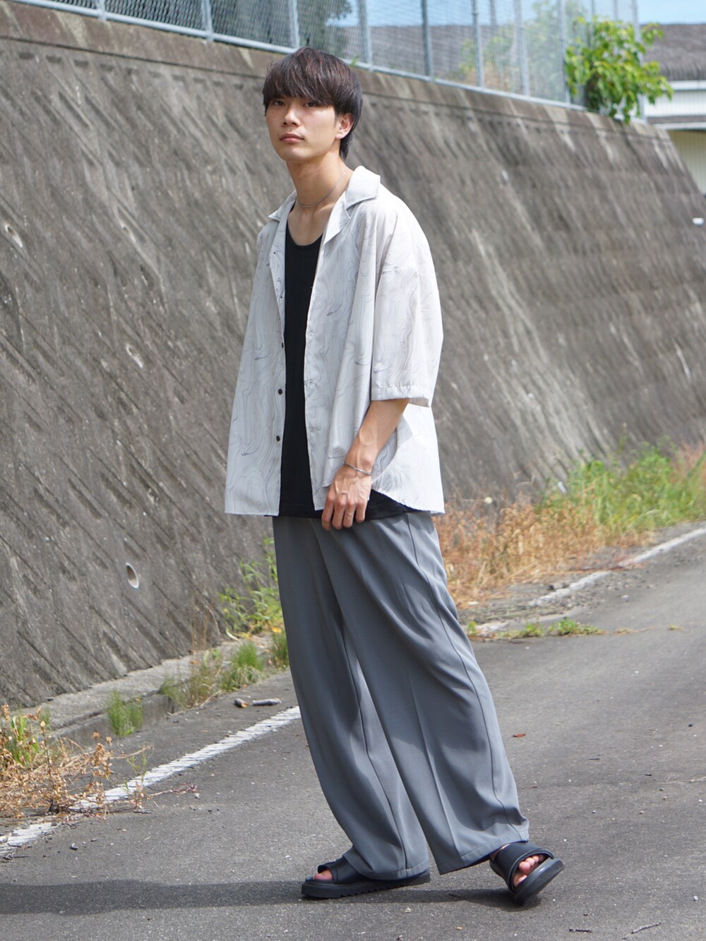 ベージュ系のシャツ/ブラウス、ブルー系のスラックス、ブラック系のサンダルを着用したメンズの夏コーディネートの2枚目の写真