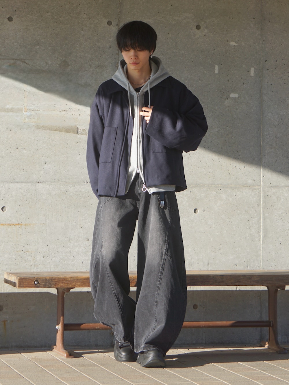 ブルー系のブルゾン、グレー系のパーカー、ブラック系のデニムパンツを着用したメンズの冬コーディネートの2枚目の写真