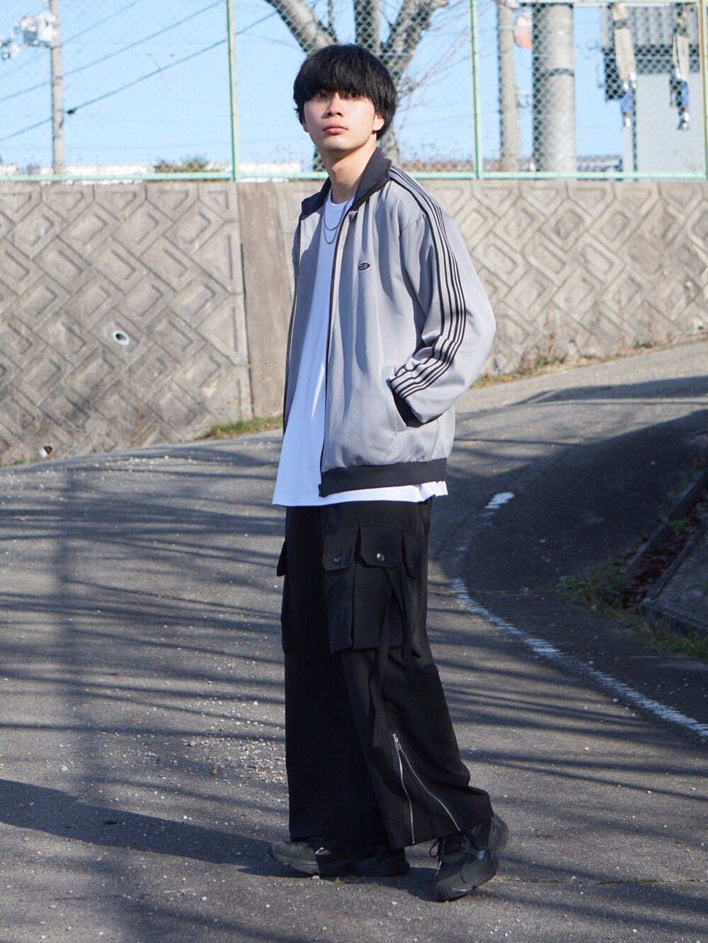 グレー系のジャージ、ホワイト系のTシャツ/カットソー、ブラック系のカーゴパンツを着用したメンズの冬コーディネートの2枚目の写真