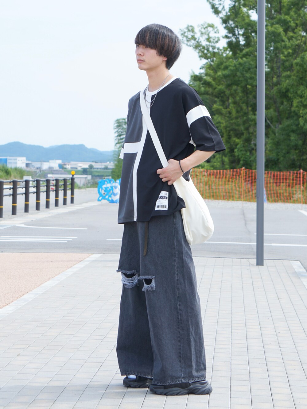 ブラック系のデニムパンツ、ブラック系のサンダル、ブラック系のTシャツ/カットソーを着用したメンズの夏コーディネートの2枚目の写真