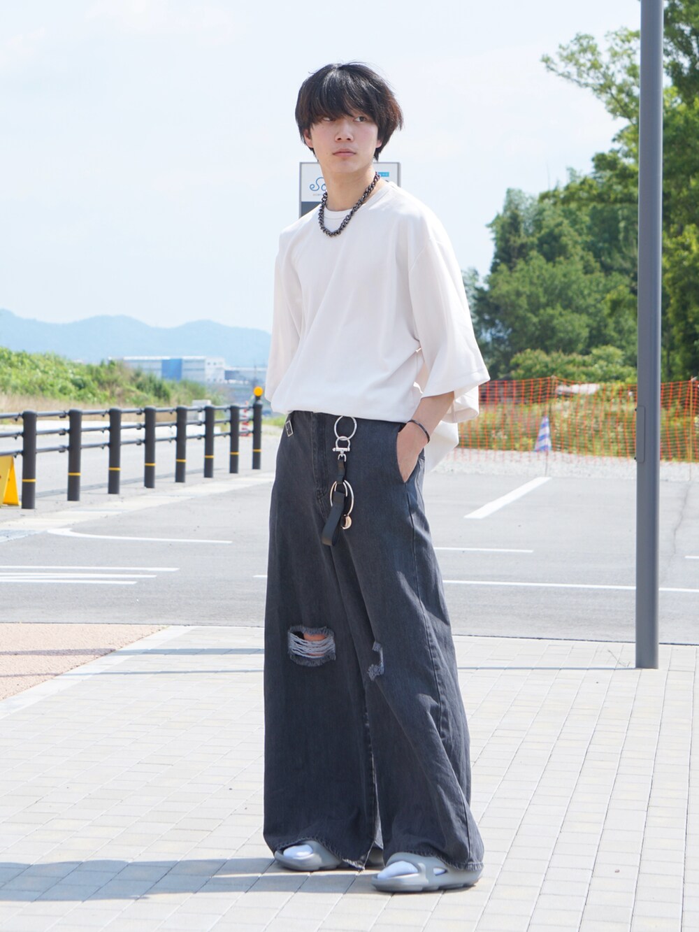 ホワイト系のTシャツ/カットソー、ブラック系のデニムパンツ、グレー系のサンダルを着用したメンズの夏コーディネートの2枚目の写真