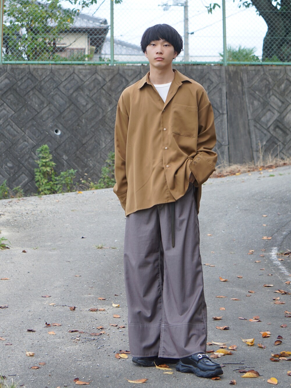 イエロー系のシャツ/ブラウス、ベージュ系のスラックス、ブラック系のスニーカーを着用したメンズの秋コーディネートの2枚目の写真