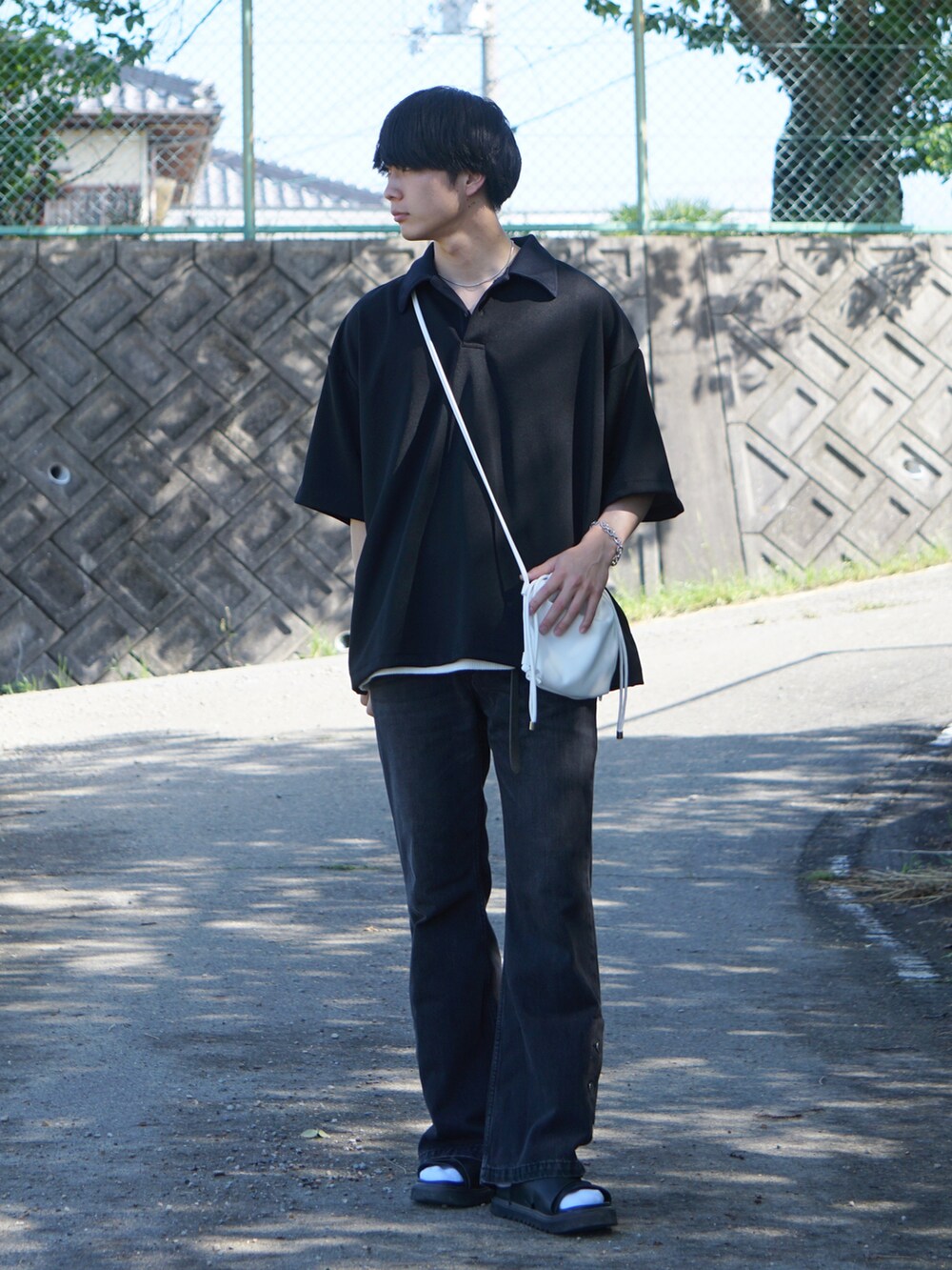 ブラック系のデニムパンツ、ブラック系のサンダル、ブラック系のポロシャツを着用したメンズの夏コーディネートの2枚目の写真