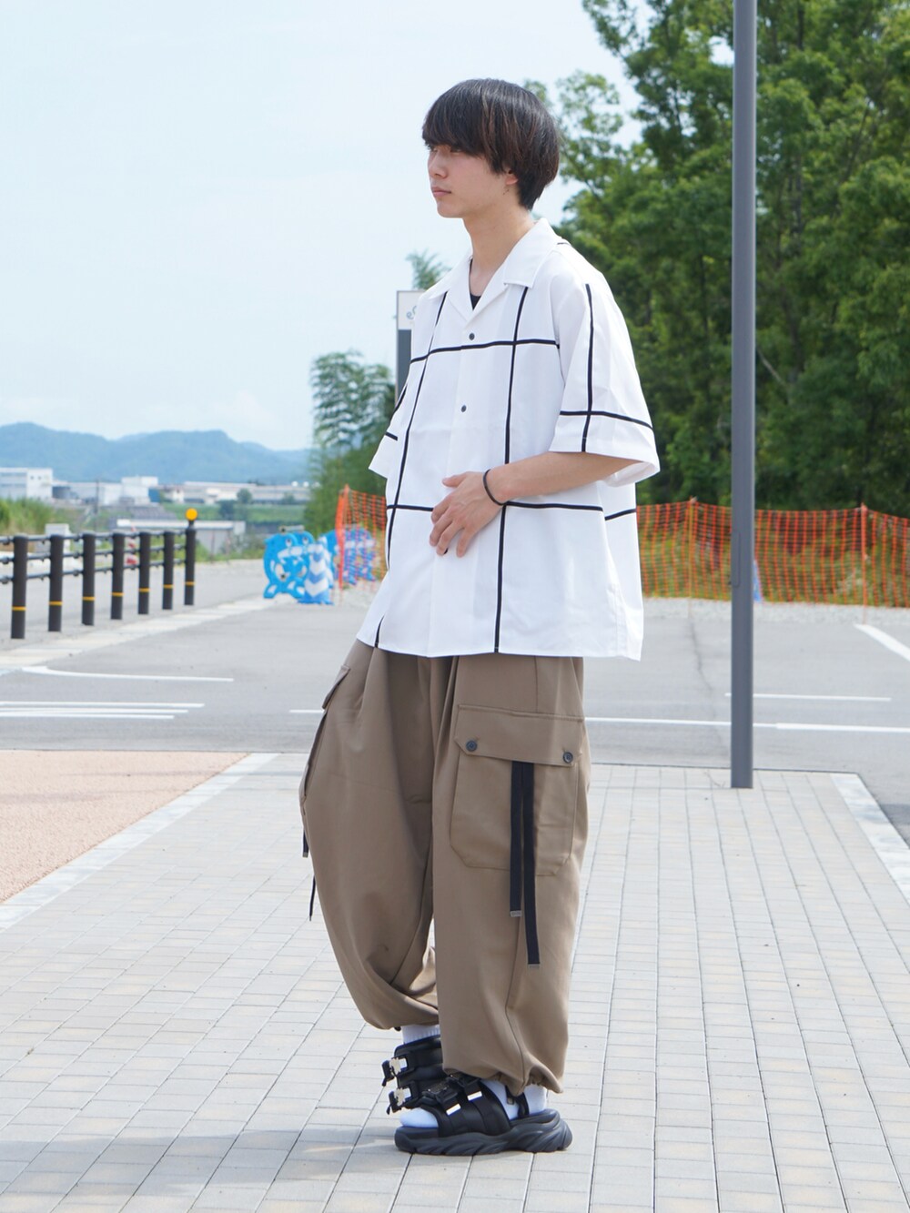 ホワイト系のシャツ/ブラウス、ベージュ系のカーゴパンツ、ブラック系のスニーカーを着用したメンズの夏コーディネートの2枚目の写真