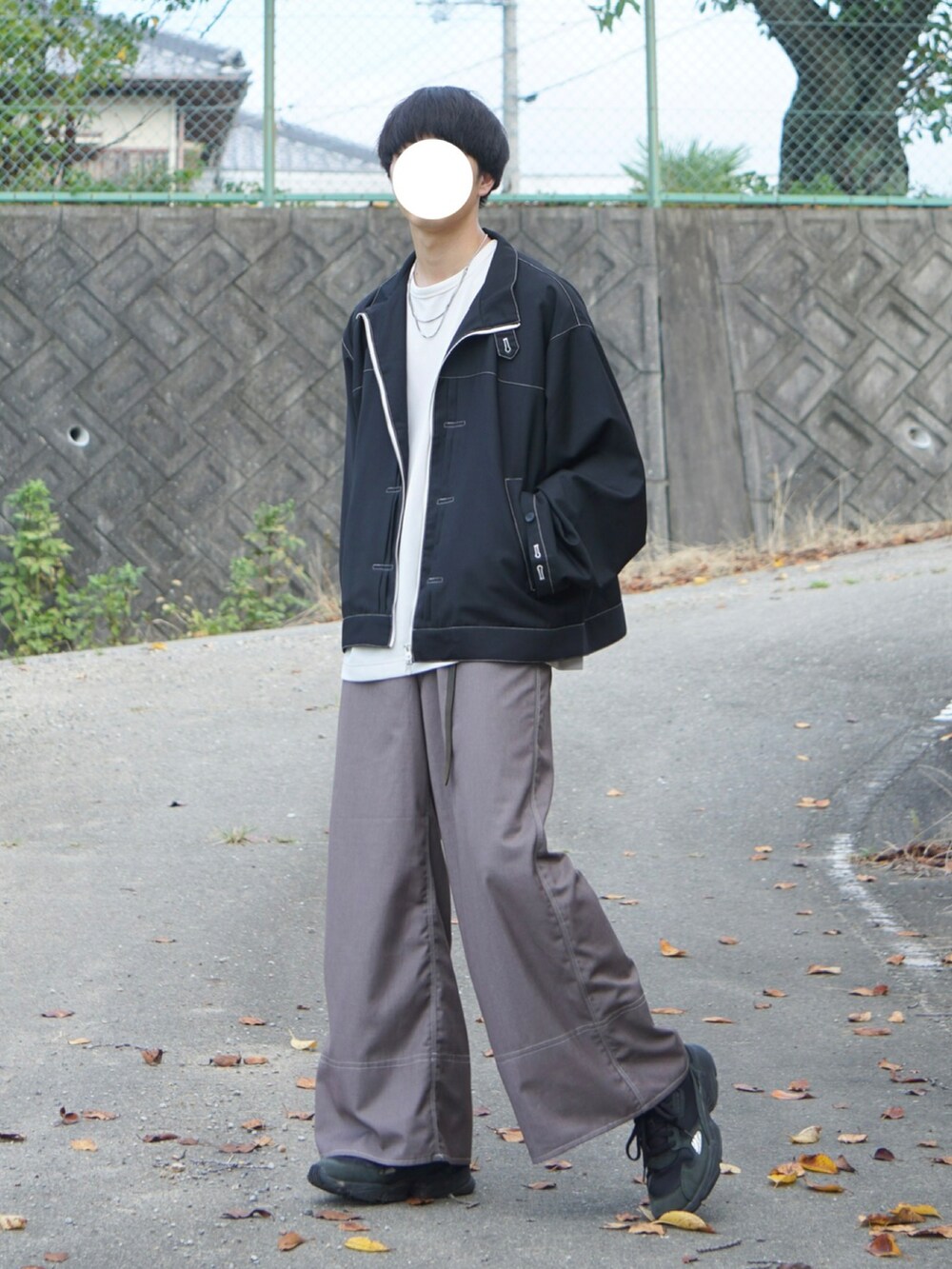 ブラック系のブルゾン、ベージュ系のスラックス、ホワイト系のTシャツ/カットソーを着用したメンズの夏コーディネートの2枚目の写真