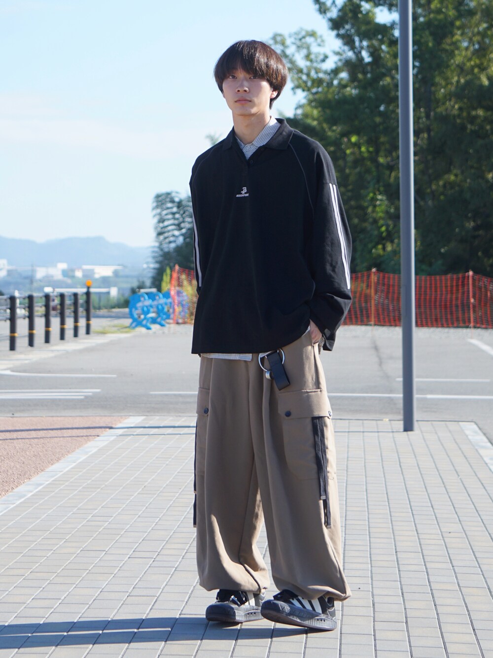 ブラック系のポロシャツ、ホワイト系のシャツ/ブラウス、ベージュ系のカーゴパンツを着用したメンズの秋コーディネートの3枚目の写真