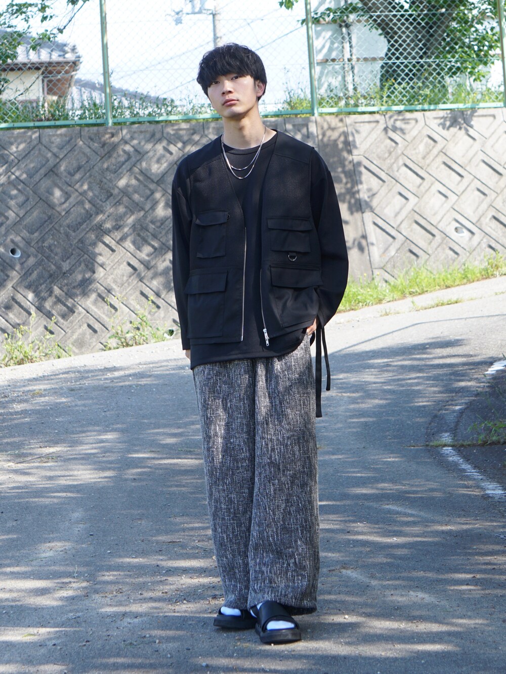 ブラック系のパンツ、ブラック系のTシャツ/カットソー、ブラック系のベストを着用したメンズの春コーディネートの2枚目の写真