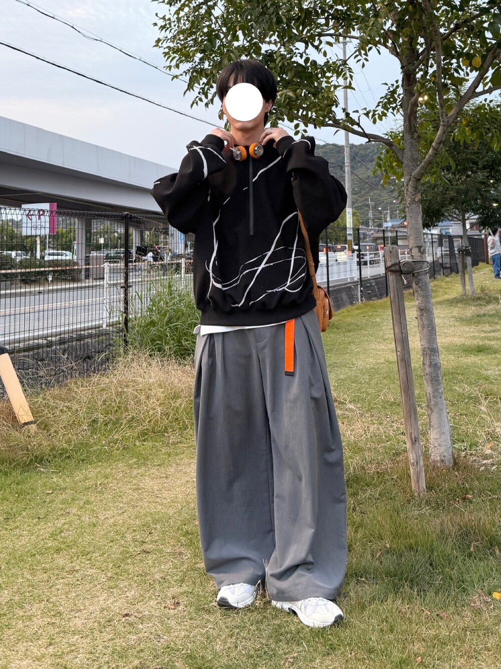 グレー系のスラックス、ベージュ系のショルダーバッグ、ホワイト系のスニーカーを着用したメンズの秋コーディネートの2枚目の写真