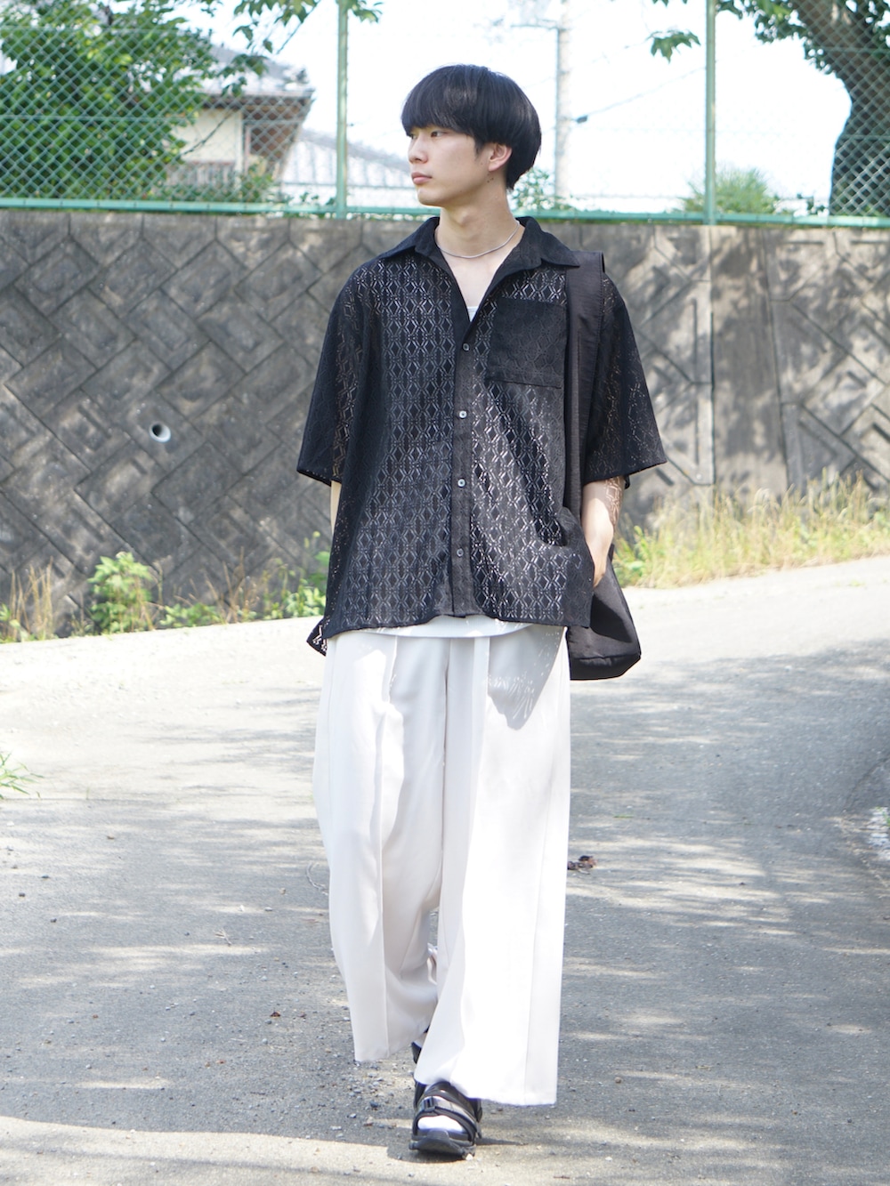 ブラック系のシャツ/ブラウス、ベージュ系のスラックス、ホワイト系のサンダルを着用したメンズの夏コーディネートの2枚目の写真