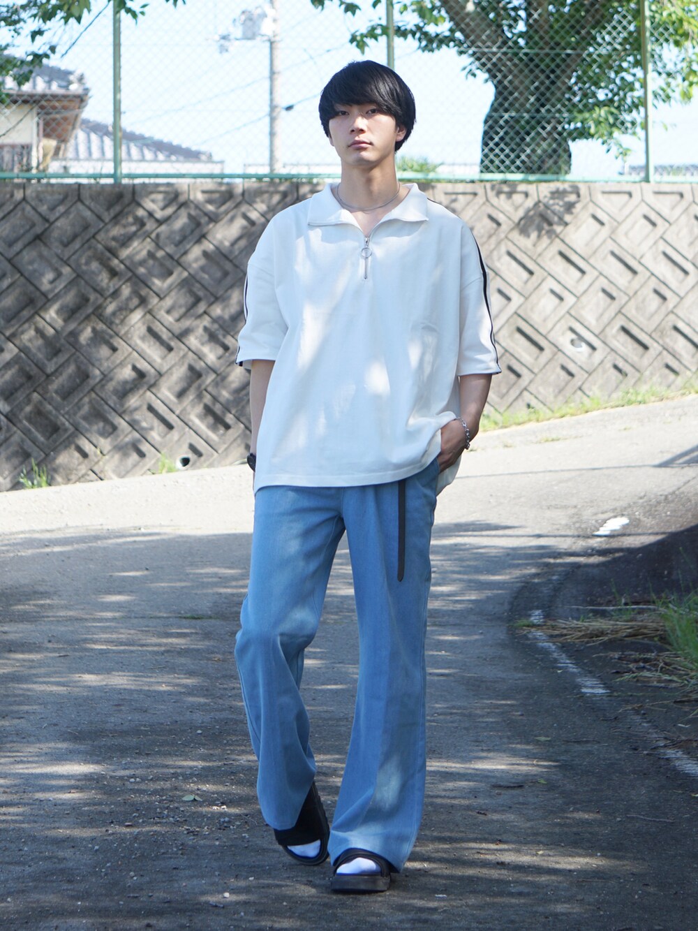 ブルー系のデニムパンツ、ホワイト系のTシャツ/カットソー、ブラック系のサンダルを着用したメンズの夏コーディネートの2枚目の写真