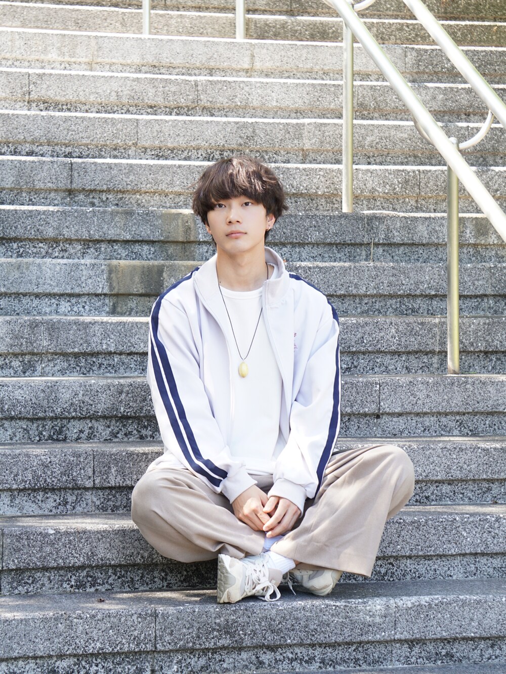 ホワイト系のジャケット/アウター、ホワイト系のTシャツ/カットソー、ベージュ系のスラックスを着用したメンズの秋コーディネートの3枚目の写真