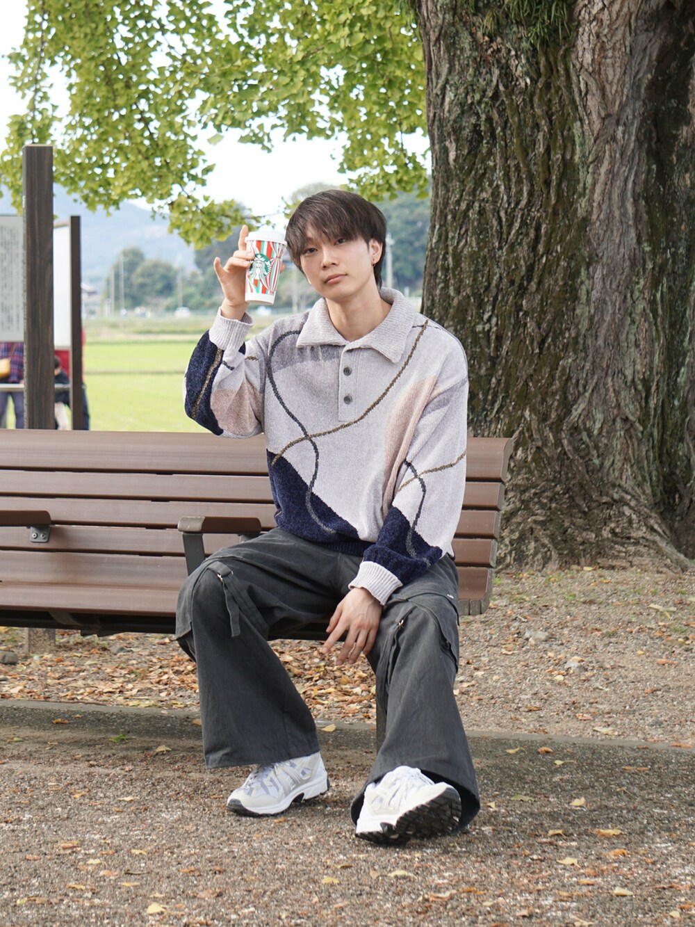グレー系のニット/セーター、ブラック系のカーゴパンツ、ホワイト系のスニーカーを着用したメンズの秋コーディネートの3枚目の写真