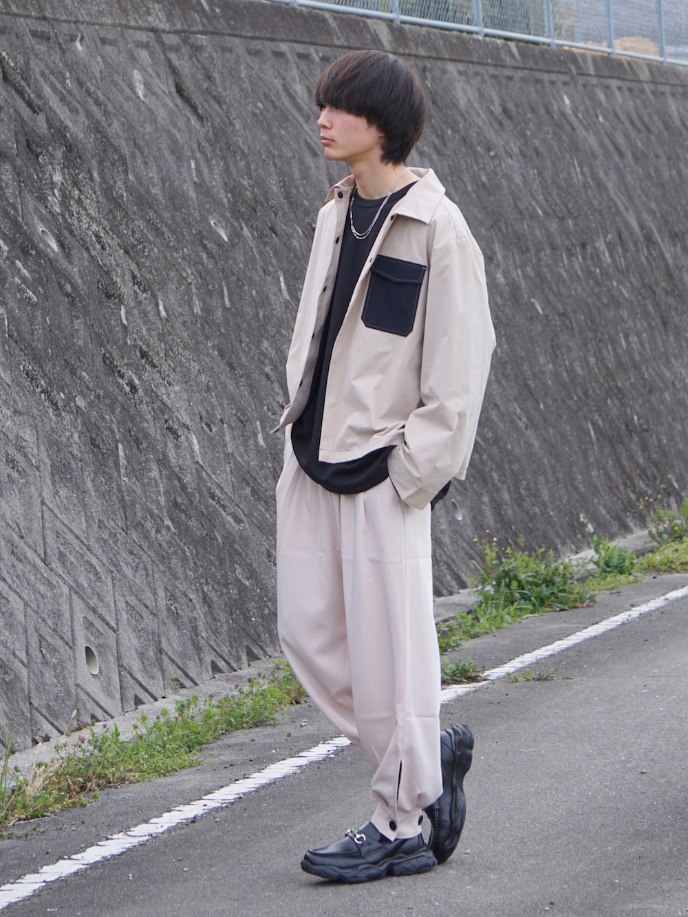 ベージュ系のブルゾン、ブラック系のTシャツ/カットソー、ベージュ系のその他パンツを着用したメンズの春コーディネートの2枚目の写真