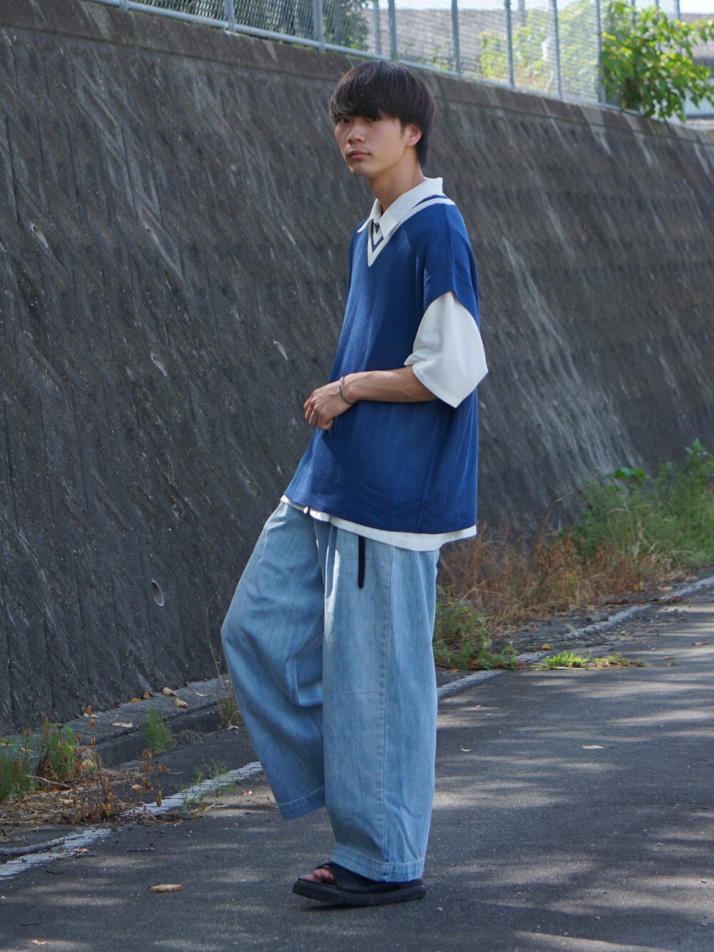 ブルー系のデニムパンツ、ブラック系のサンダル、ホワイト系のシャツ/ブラウスを着用したメンズの夏コーディネートの3枚目の写真