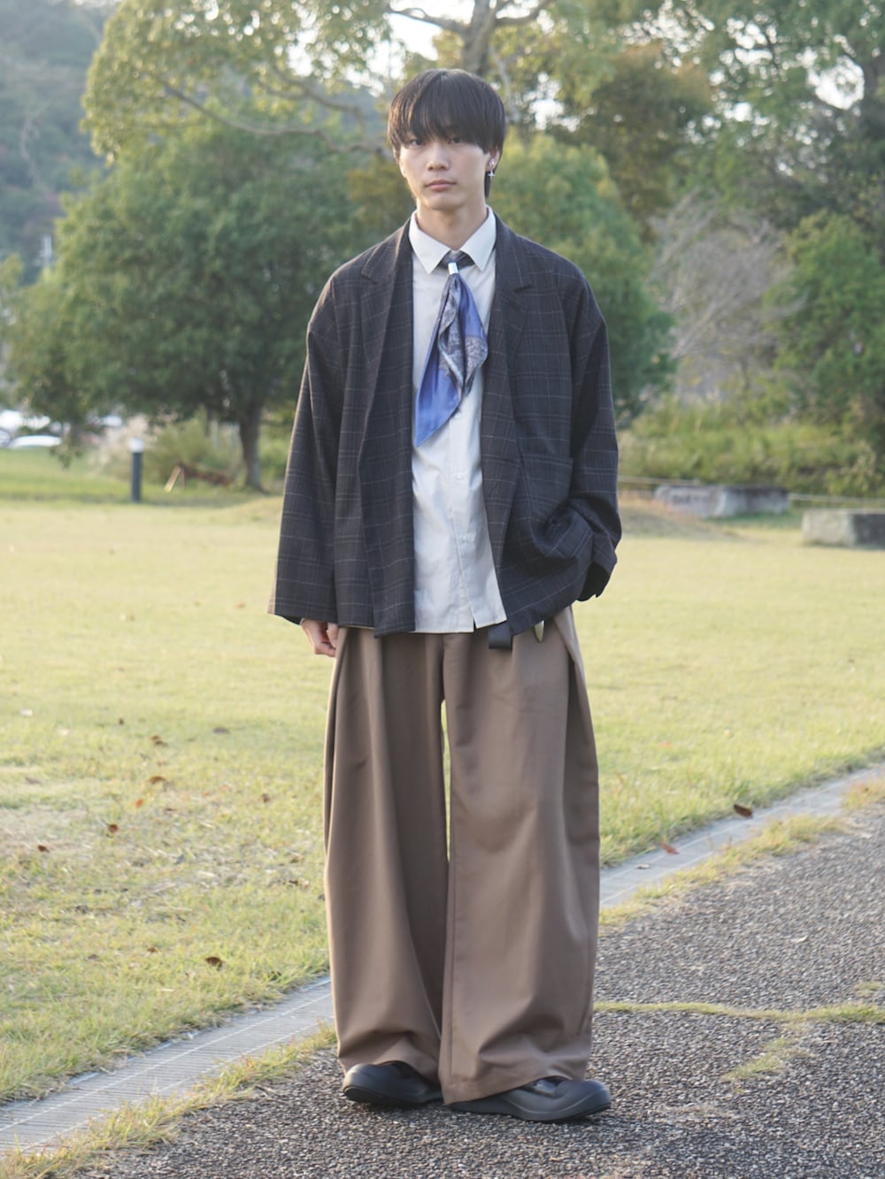 ブラック系のテーラードジャケット、ブラウン系のスラックス、ブラック系のスニーカーを着用したメンズの秋コーディネートの2枚目の写真