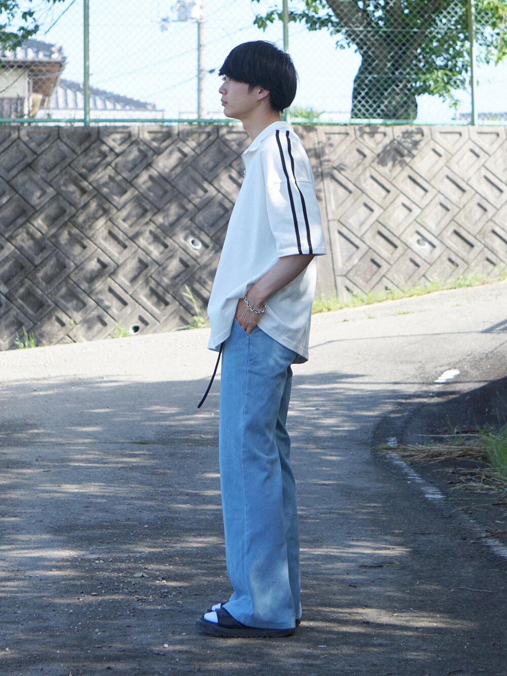 ブルー系のデニムパンツ、ホワイト系のTシャツ/カットソー、ブラック系のサンダルを着用したメンズの夏コーディネートの3枚目の写真
