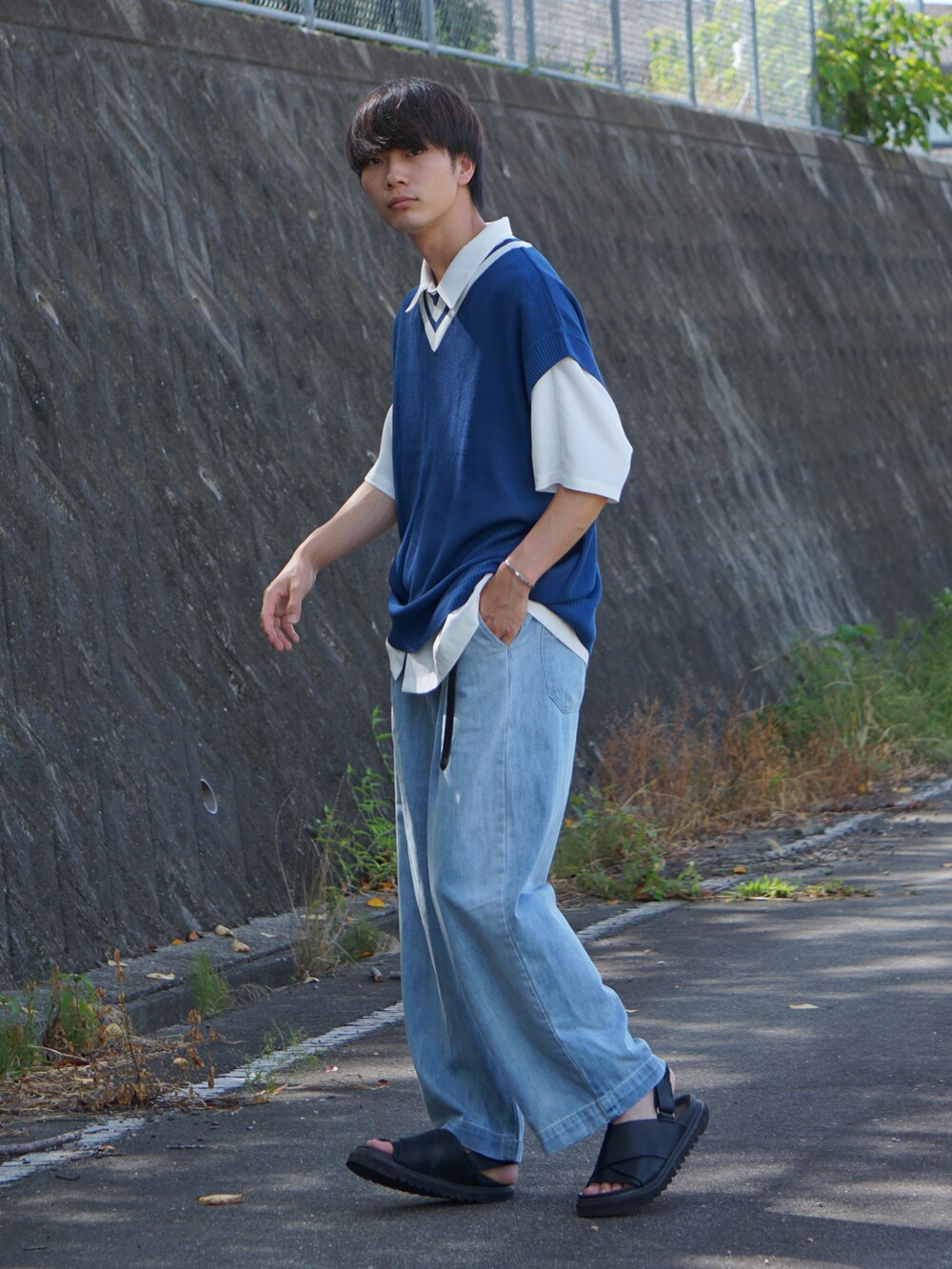 ブルー系のデニムパンツ、ブラック系のサンダル、ホワイト系のシャツ/ブラウスを着用したメンズの夏コーディネートの2枚目の写真