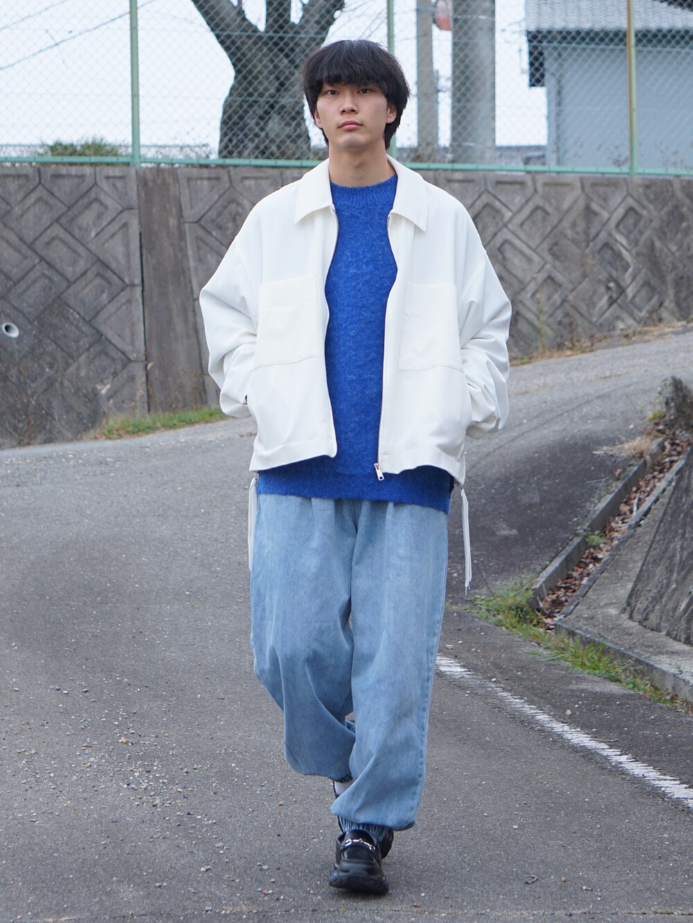 ブラック系のスニーカー、ブルー系のデニムパンツ、ホワイト系のブルゾンを着用したメンズの冬コーディネートの2枚目の写真